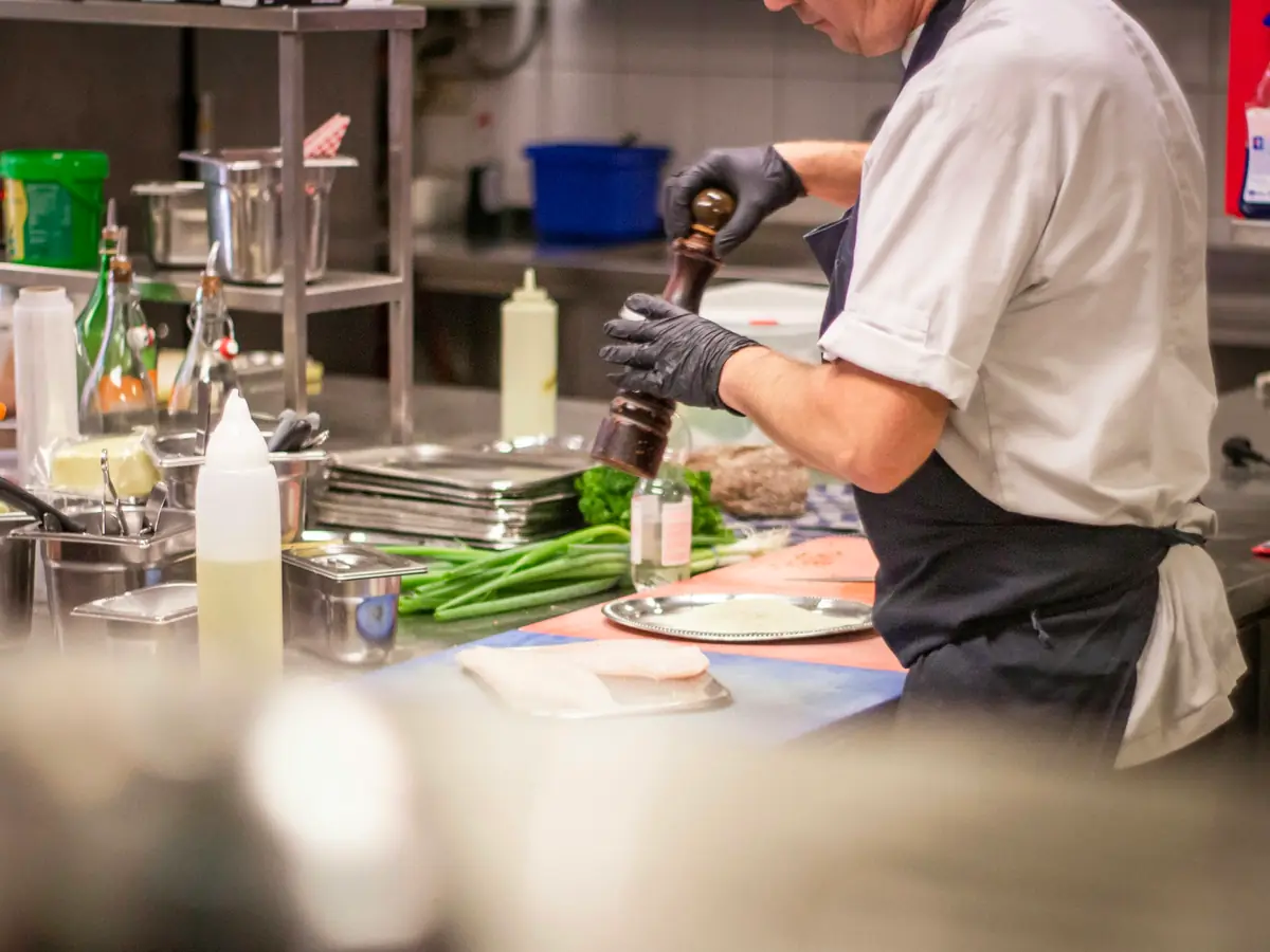 A cook finishing a plate with fresh herbs