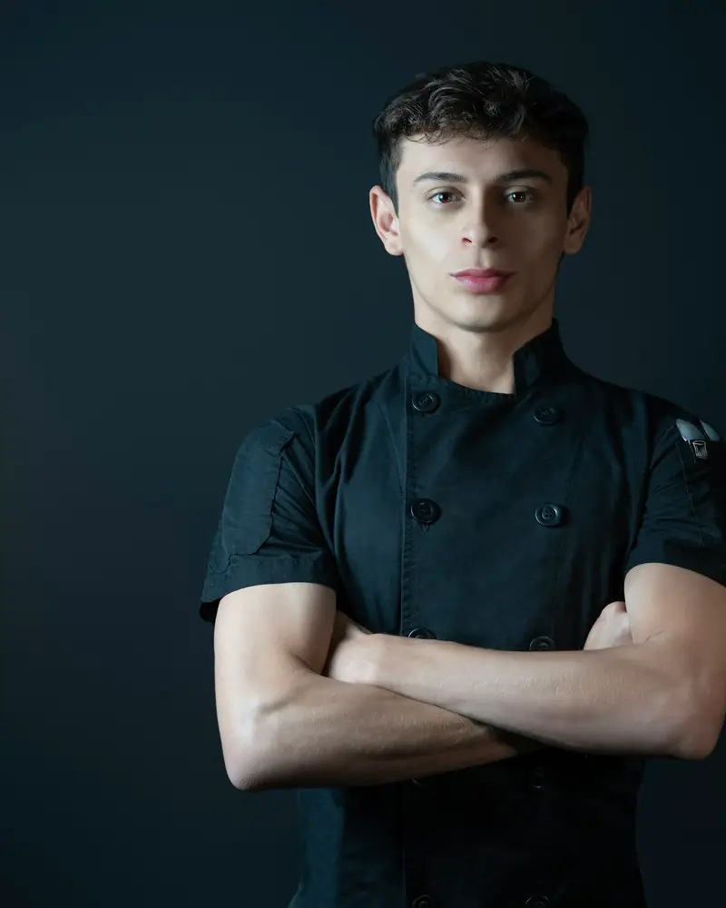 Head chef, arms crossed, in the kitchen